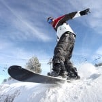 SNowboarder på vej ud over bakke med blå himmel i baggrunden